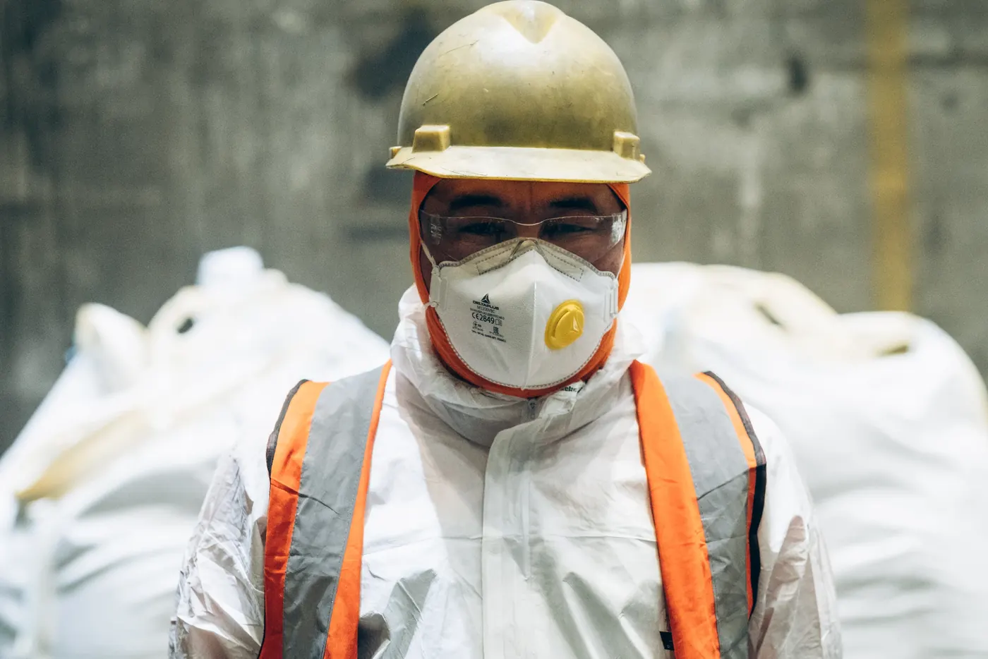 Worker in respirator in front of bulk bags