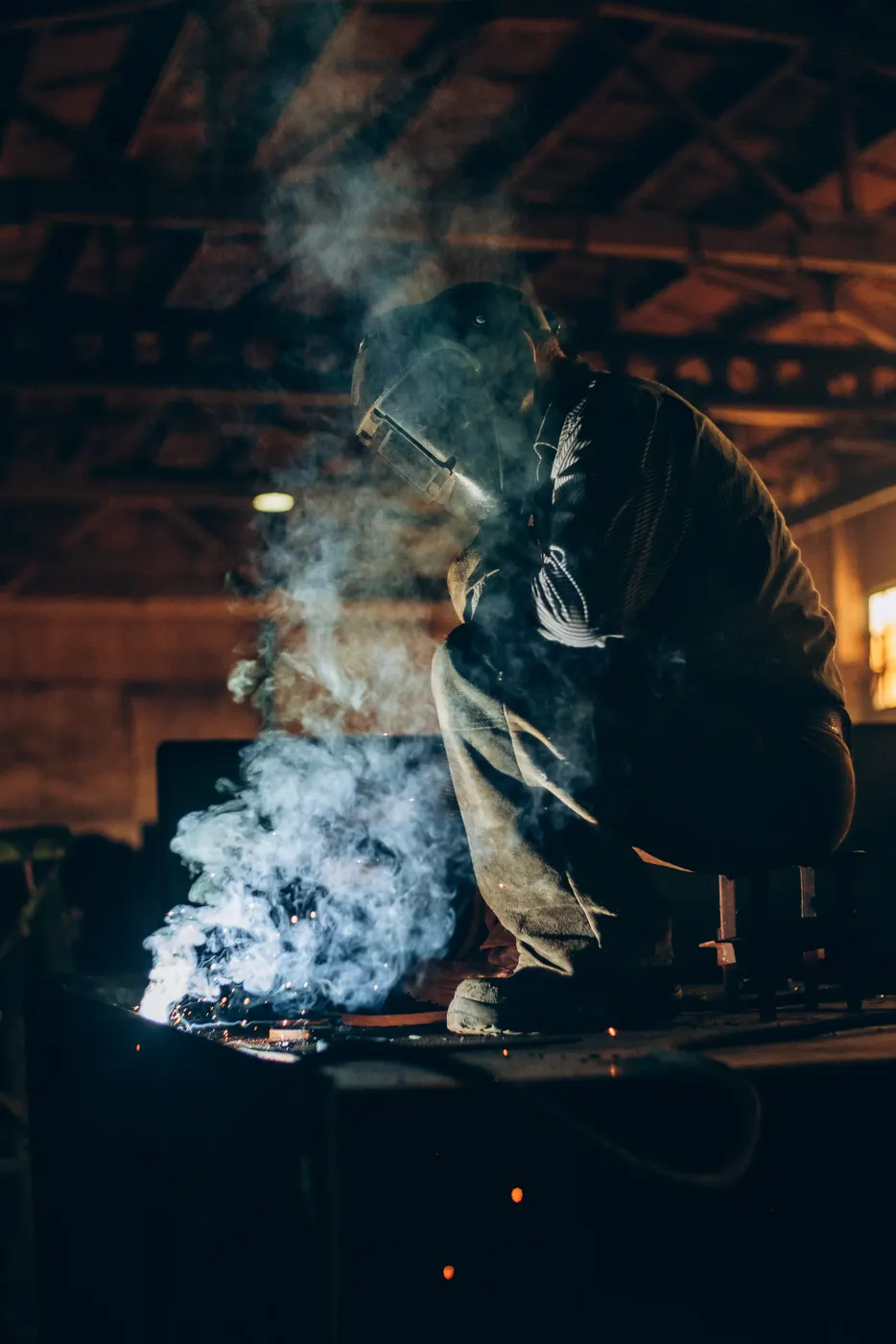 Welder crouching in a cloud of smoke